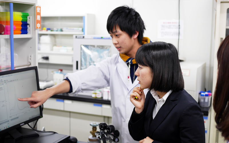 Ryuichi Shinohara (rear), second-year graduate student, explains the component analysis of artificial blood.